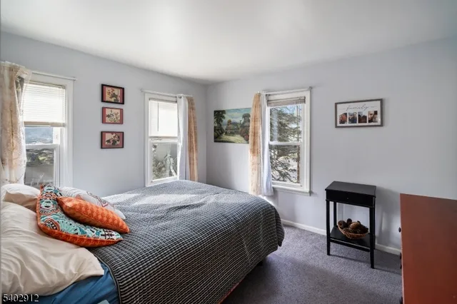 a bedroom with a bed a dresser and next to a window