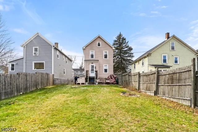 a view of a house with a yard and a large tree