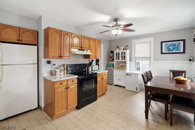 a kitchen with stainless steel appliances granite countertop a refrigerator a sink dishwasher a stove and white countertops with wooden floor