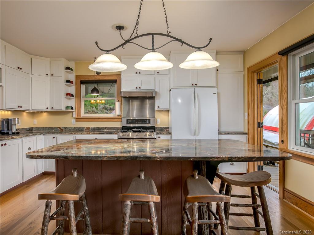 390 Grandview Road Canton, NC 28716 - Photo 12 of 42 a kitchen with stainless steel appliances granite countertop a table chairs in it and wooden floors