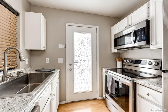 a kitchen with stainless steel appliances granite countertop grey cabinets a stove a microwave and a sink