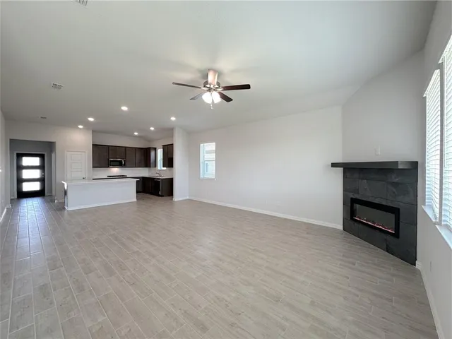 a view of an empty room with a kitchen and a fireplace