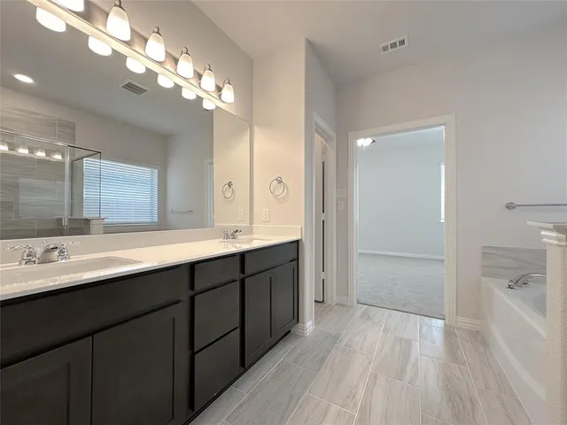 a spacious bathroom with a double vanity sink a large mirror and shower