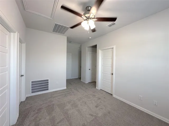 an empty room with chandelier fan and windows