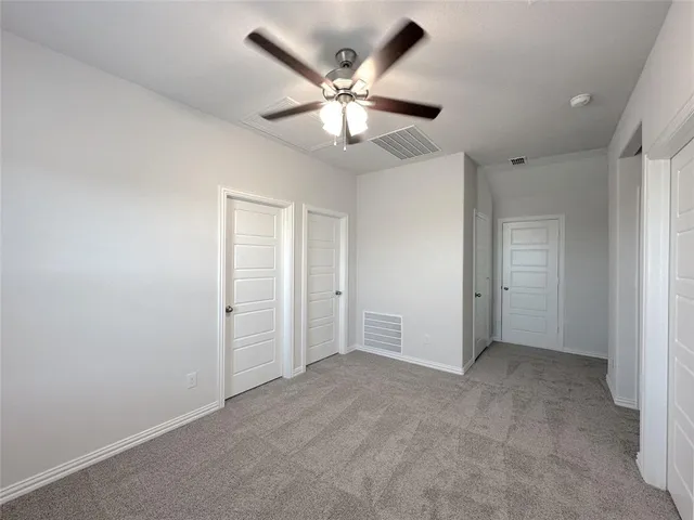 an empty room with closet and a ceiling fan