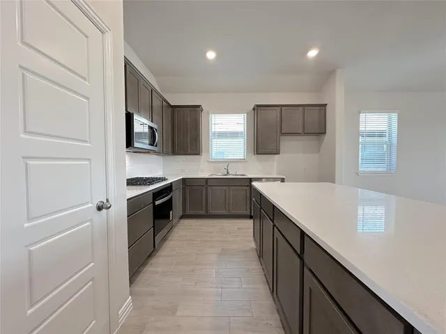 a kitchen with stainless steel appliances granite countertop a sink and dishwasher a stove top oven with wooden floor