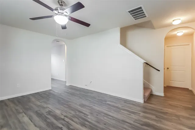 an empty room with wooden floor and ceiling fan