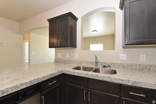 241 West Ridge Road Saratoga Springs, UT 84045 - Photo 8 of 21 Kitchen featuring dark wood-finish cabinetry, light-toned countertops, and a double basin stainless steel sink