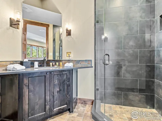 a bathroom with a granite countertop sink a mirror and shower
