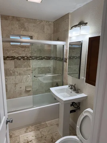 a bathroom with a sink a toilet and shower