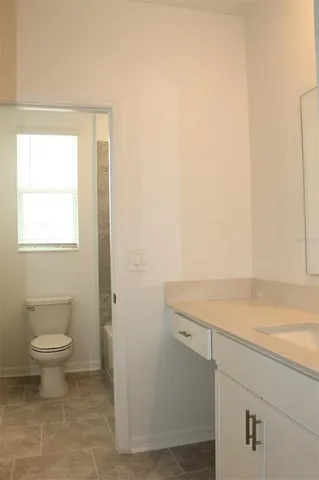a bathroom with a sink a toilet and a window