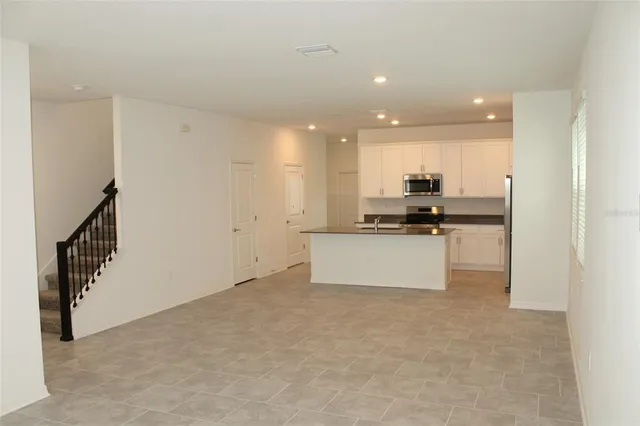 a view of kitchen with kitchen island white cabinets and stainless steel appliances