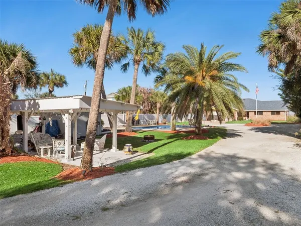 a view of a patio with couches table and chairs with plants and trees