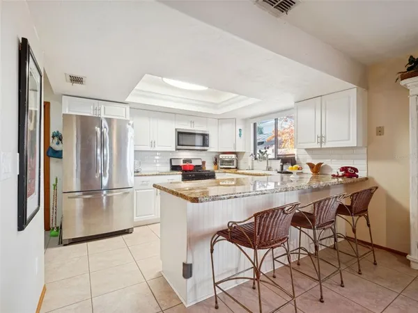 a living room with furniture kitchen view and a large window