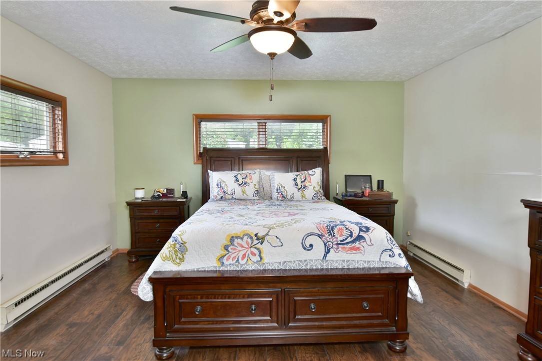 1711 Salt Springs Road Mineral Ridge, OH 44440 - Photo 23 of 35 Hardwood floored bedroom with a textured ceiling, baseboard heating, and ceiling fan