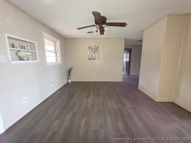 a view of a livingroom with wooden floor a ceiling fan and windows