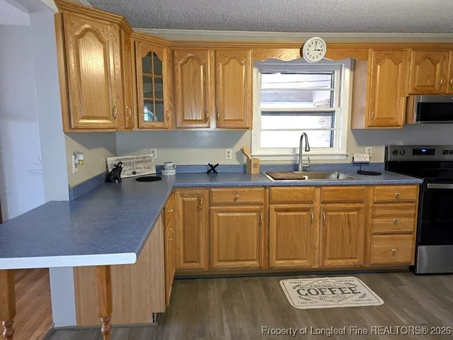 a kitchen with granite countertop a sink a stove cabinets and wooden floor