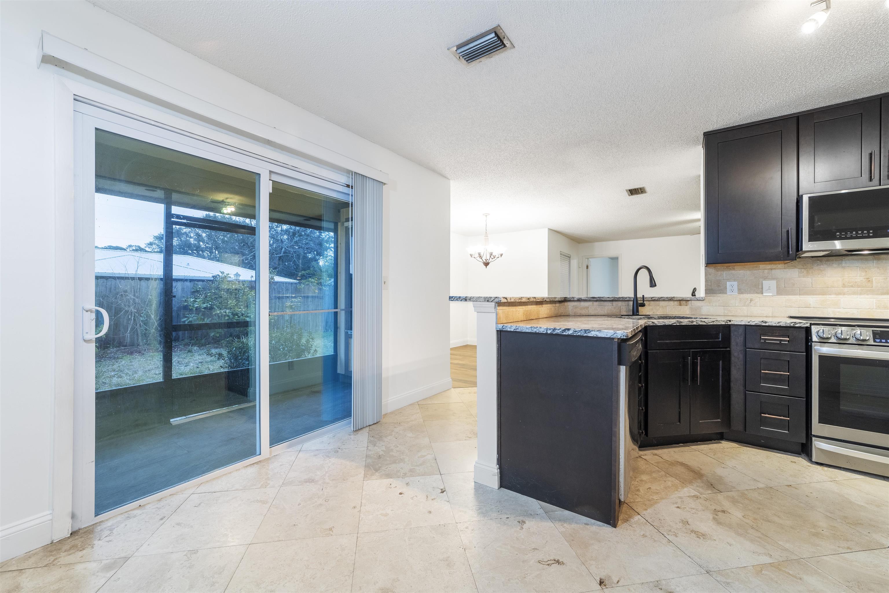 111 Lobelia Road St. Augustine, FL 32086 - Photo 16 of 46 a kitchen with stainless steel appliances granite countertop a stove a sink and a refrigerator with wooden floor