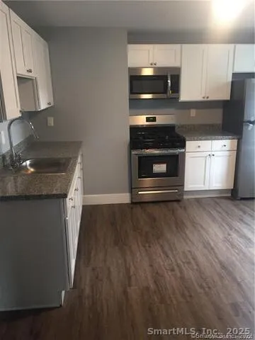 a kitchen with granite countertop a stove and a wooden floor