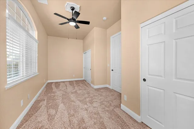 a view of a white house with large trees and wooden fence