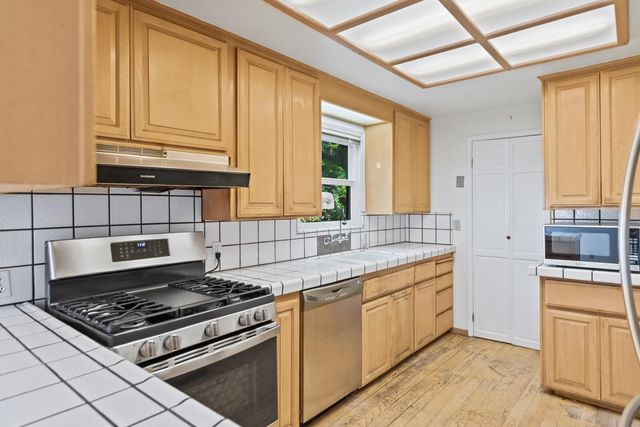 a kitchen with stainless steel appliances granite countertop a stove a sink and a microwave