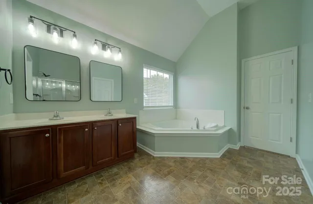 a spacious bathroom with a tub sink and mirror