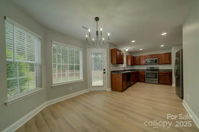 an empty room with wooden floor a fireplace and windows