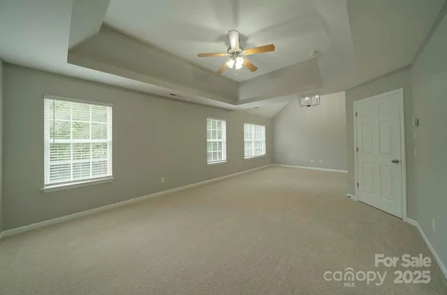 en empty room with windows and chandelier fan