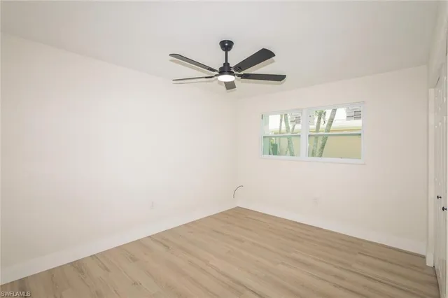 an empty room with wooden floor ceiling fan and windows