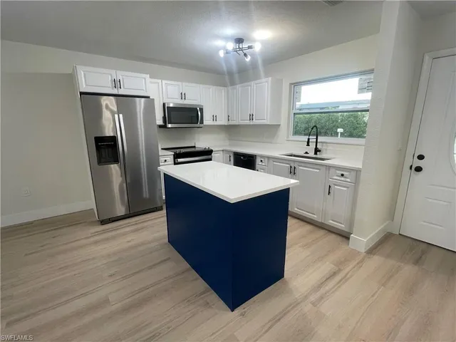 a kitchen with stainless steel appliances granite countertop a stove a sink dishwasher a refrigerator and a oven with wooden floor