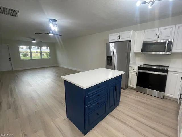 a kitchen with stainless steel appliances a kitchen island hardwood floor and a sink
