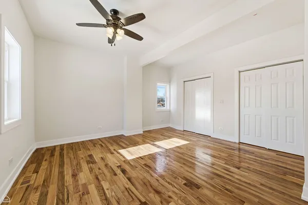 a view of a big room with wooden floor and a chandelier fan