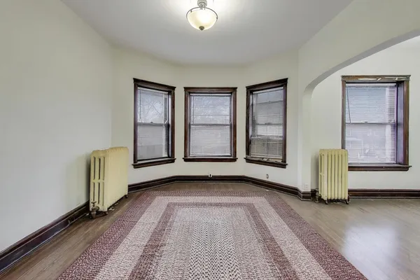 a view of an empty room with wooden floor and a ceiling fan