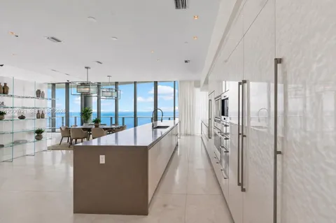 a living room with stainless steel appliances furniture a large window and a chandelier
