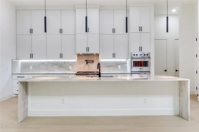 a view of kitchen with stainless steel appliances granite countertop white cabinets and sink