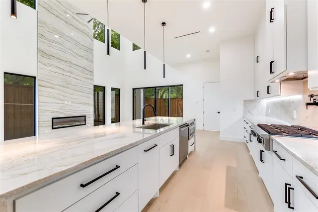 a large white kitchen with granite countertop a stove and a sink