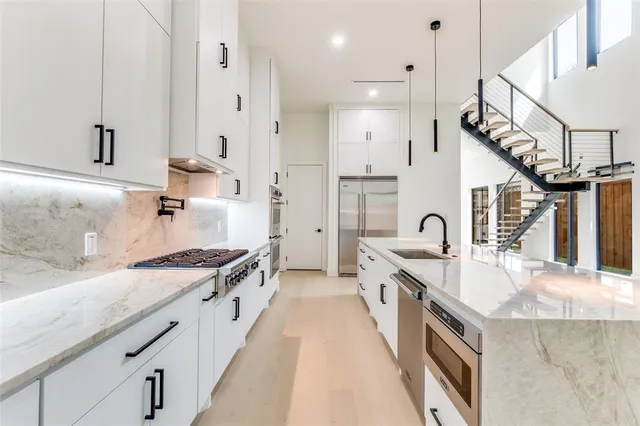 a open kitchen with stainless steel appliances granite countertop a sink a stove and a wooden floors