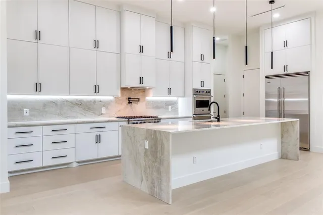 a kitchen with granite countertop a sink white cabinets and stainless steel appliances