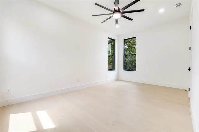 an empty room with windows and fan