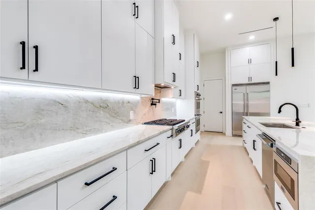 a large kitchen with stainless steel appliances granite countertop a lot of counter space and wooden floors