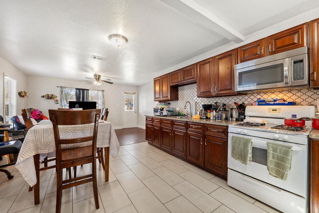 5309 Prock Lane Austin, TX 78721 - Photo 20 of 22 a kitchen with stainless steel appliances granite countertop a stove a sink dishwasher a dining table and chairs with wooden cabinets