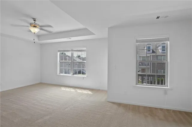 an empty room with windows and fan