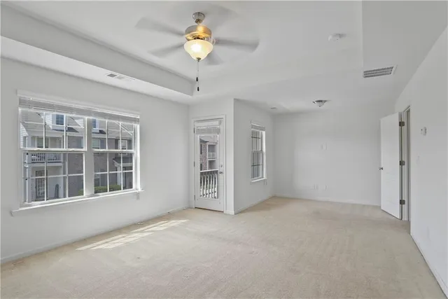 a view of an empty room with a window and chandelier fan