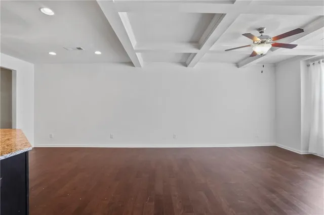 an empty room with wooden floor and fan