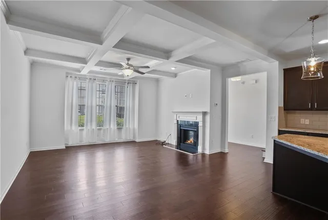 a view of an empty room with wooden floor a fireplace and a window