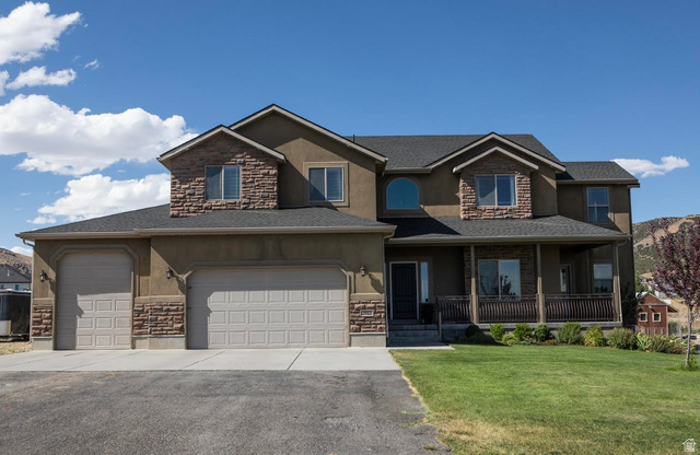2912 West Rim Rock Drive Stockton, UT 84071 - Photo 1 of 1 View of front of home featuring stone siding, covered porch, a front lawn, stucco siding, and driveway