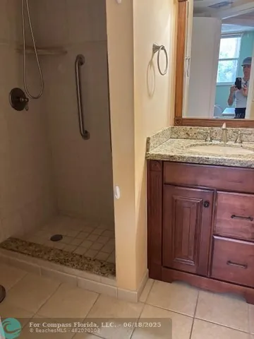 a bathroom with a granite countertop sink a mirror and shower