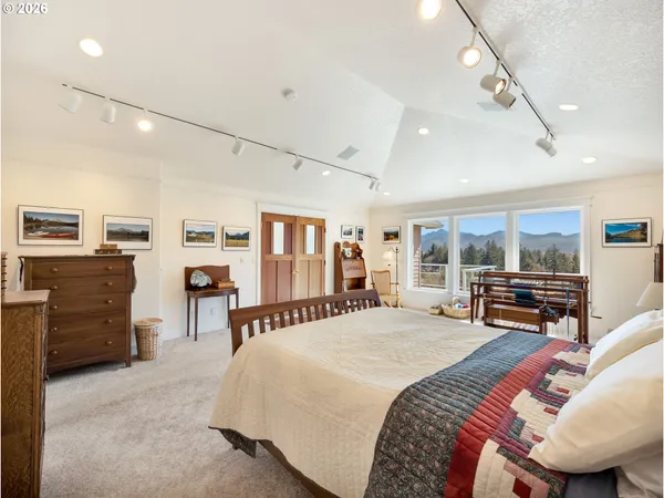 a spacious bedroom with a bed a dresser and large windows