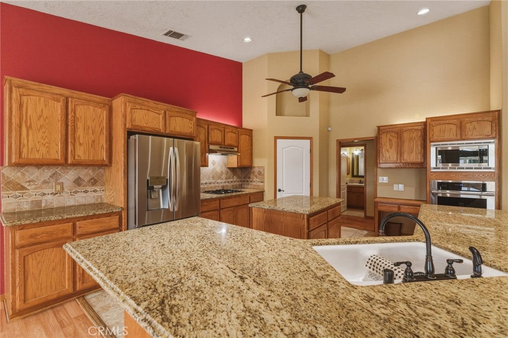 19501 Kinai Road Apple Valley, CA 92307 - Photo 23 of 49 a kitchen with stainless steel appliances kitchen island granite countertop a sink refrigerator and cabinets