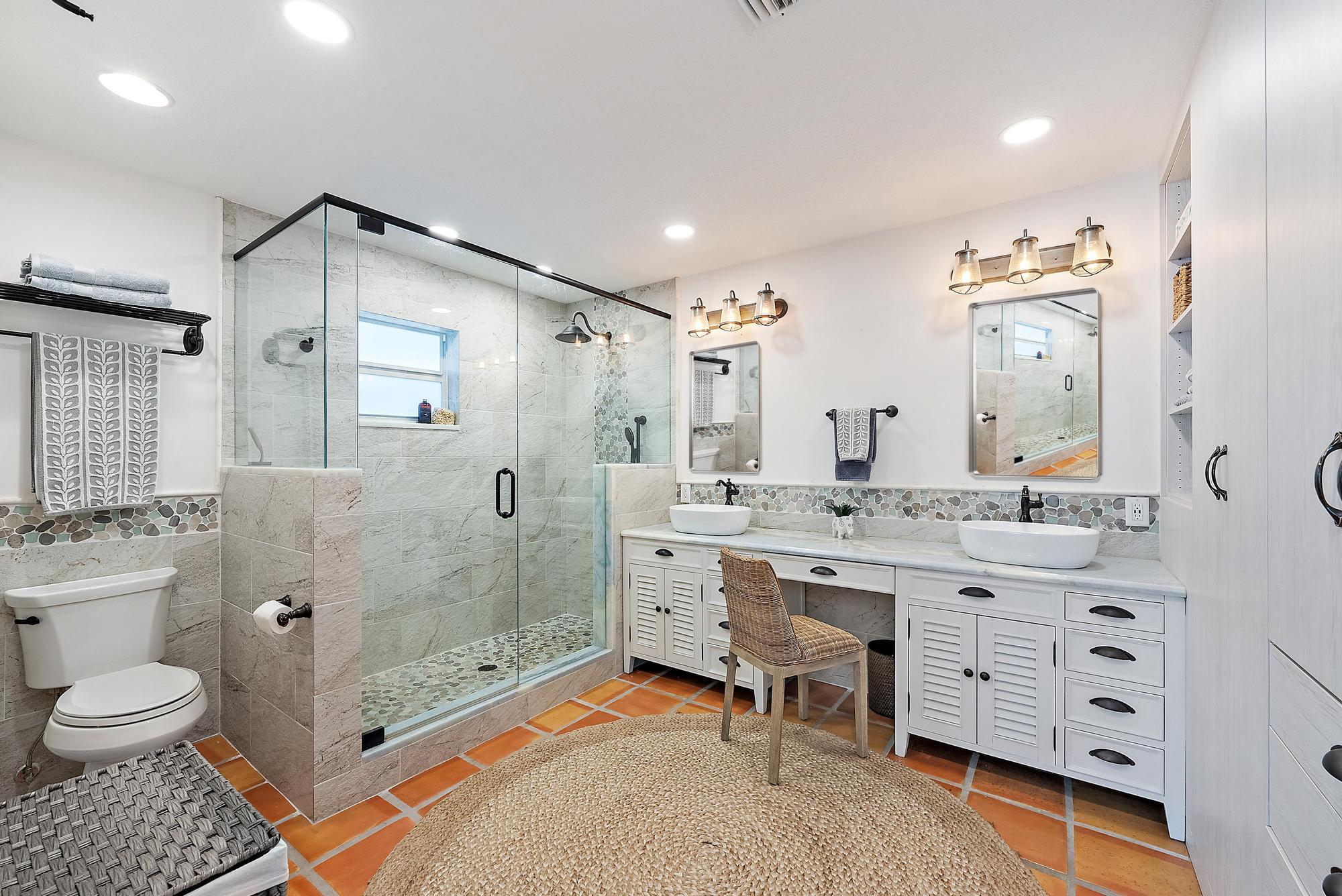 12821 Ellison Wilson Road North Palm Beach, FL 33408 - Photo 18 of 40 a bathroom with a granite countertop sink toilet a mirror a vanity and shower